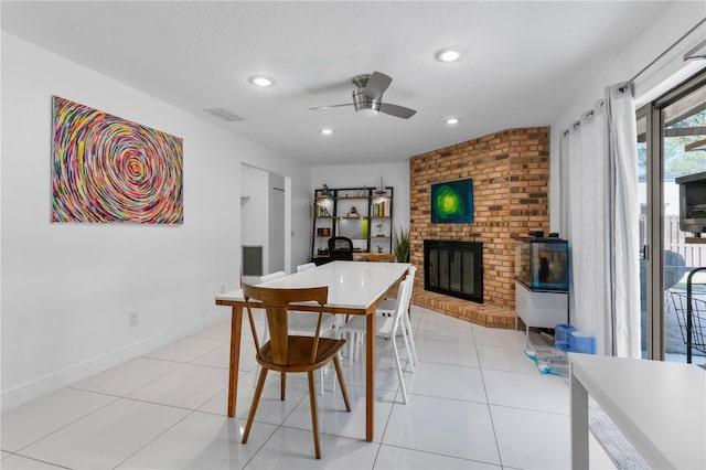 dining area with a fireplace, a textured ceiling, baseboards, and light tile patterned floors