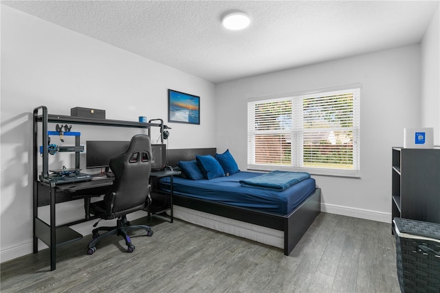 bedroom with a textured ceiling, baseboards, and wood finished floors