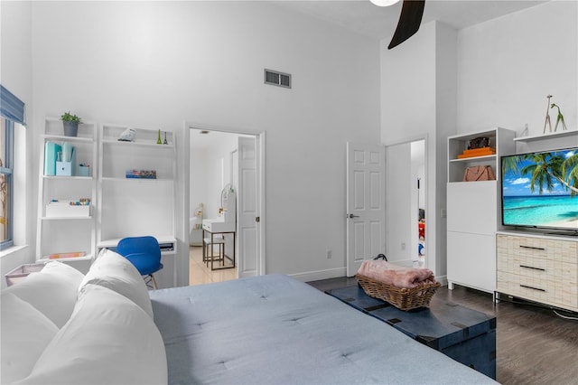 bedroom featuring baseboards, visible vents, a ceiling fan, wood finished floors, and a high ceiling