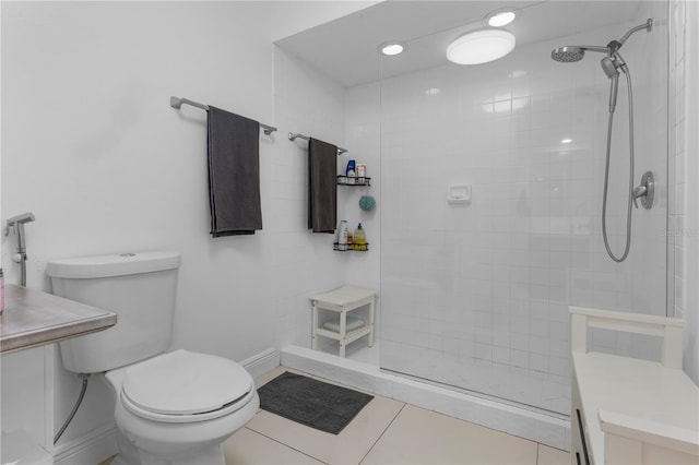 full bath with baseboards, a tile shower, toilet, and tile patterned floors