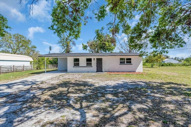 ranch-style home with an attached carport, concrete driveway, fence, and stucco siding