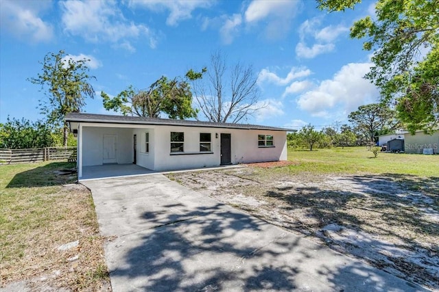 view of front of property with concrete driveway, an attached carport, a front yard, and fence