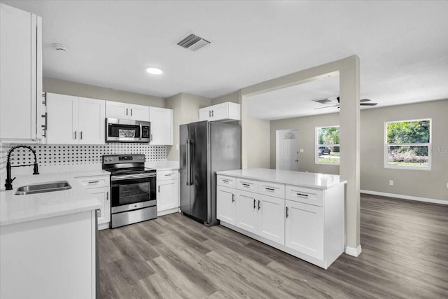 kitchen featuring tasteful backsplash, visible vents, stainless steel appliances, light wood-type flooring, and a sink