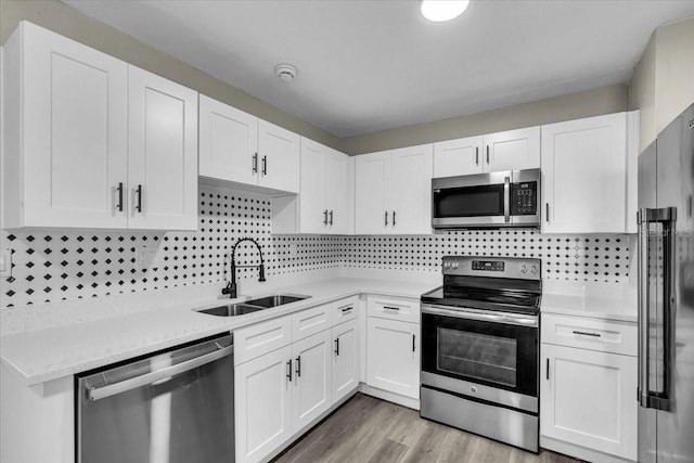 kitchen featuring appliances with stainless steel finishes, white cabinetry, a sink, and tasteful backsplash