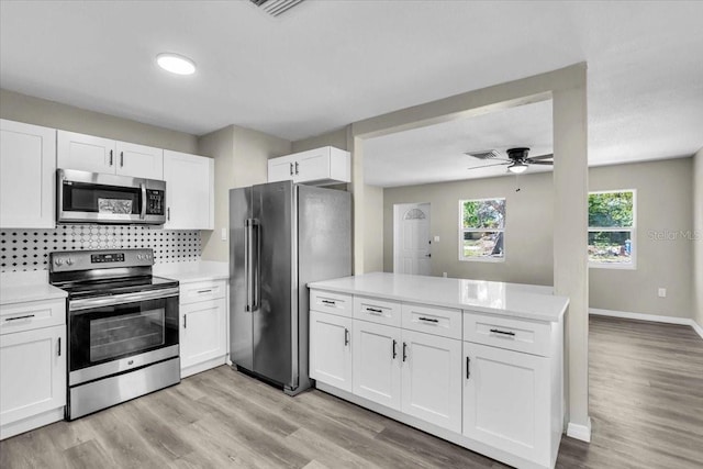 kitchen featuring stainless steel appliances, tasteful backsplash, light countertops, white cabinetry, and a peninsula