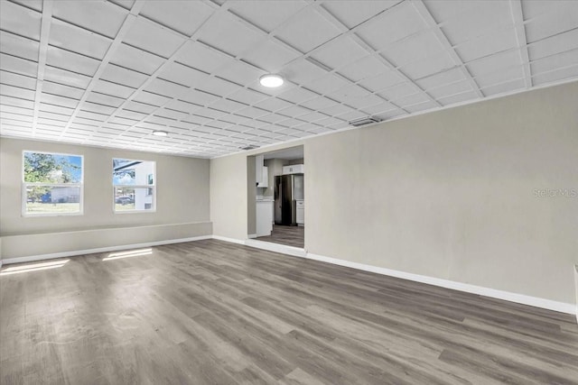 spare room with dark wood-style flooring, a paneled ceiling, and baseboards