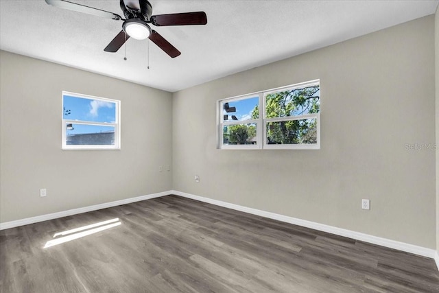 unfurnished room with ceiling fan, dark wood-type flooring, and baseboards