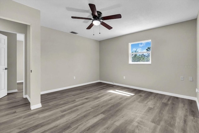 unfurnished room featuring a ceiling fan, visible vents, baseboards, and wood finished floors