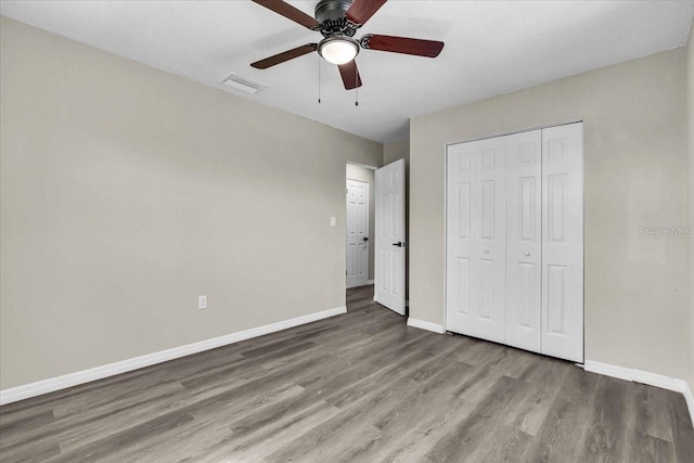 unfurnished bedroom featuring a closet, visible vents, baseboards, and wood finished floors