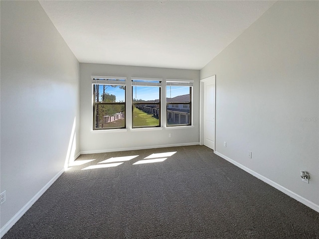 empty room with dark colored carpet and baseboards