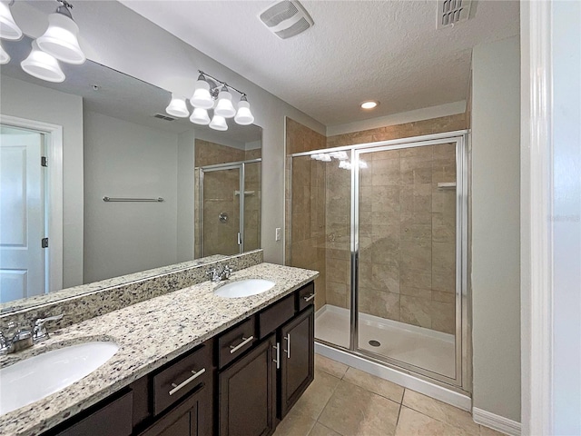 bathroom featuring tile patterned flooring, a shower stall, visible vents, and a sink