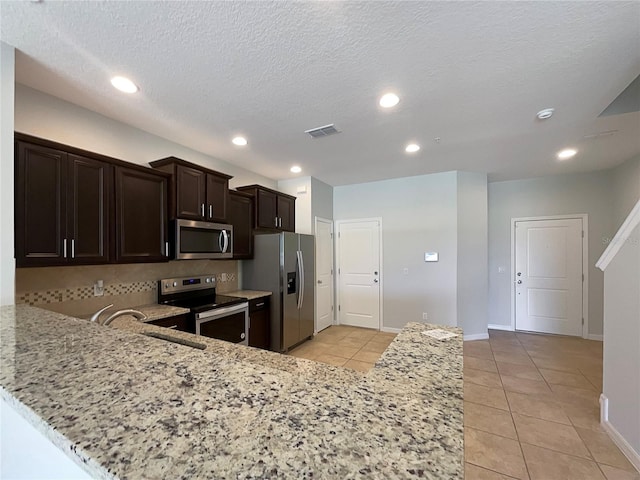 kitchen featuring light tile patterned floors, stainless steel appliances, light stone countertops, and visible vents