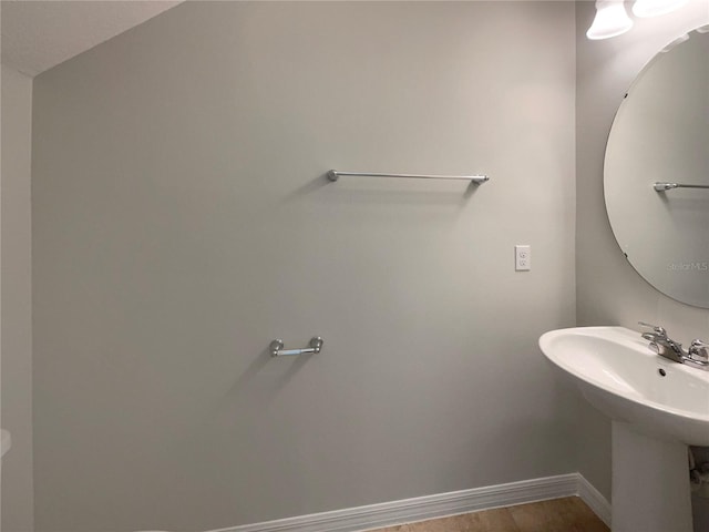 bathroom with wood finished floors, baseboards, and a sink