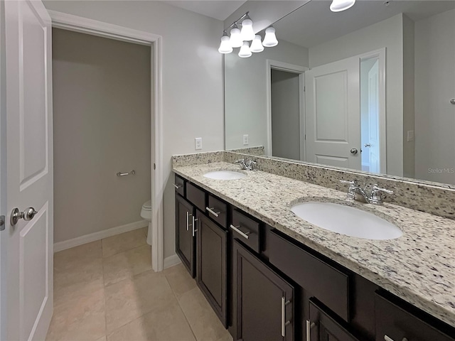 full bathroom with a sink, baseboards, toilet, and double vanity