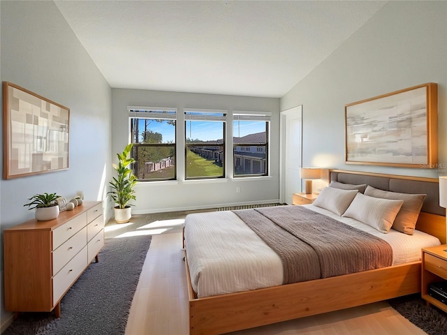 bedroom with vaulted ceiling and wood finished floors