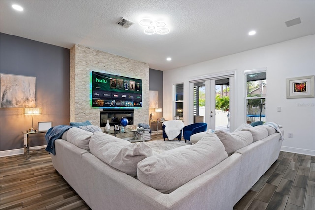 living area featuring dark wood-style floors, visible vents, a textured ceiling, and french doors