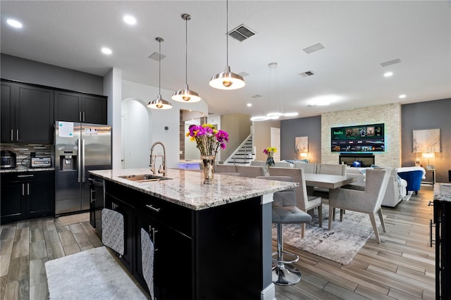 kitchen featuring visible vents, dark cabinetry, stainless steel refrigerator with ice dispenser, and a sink