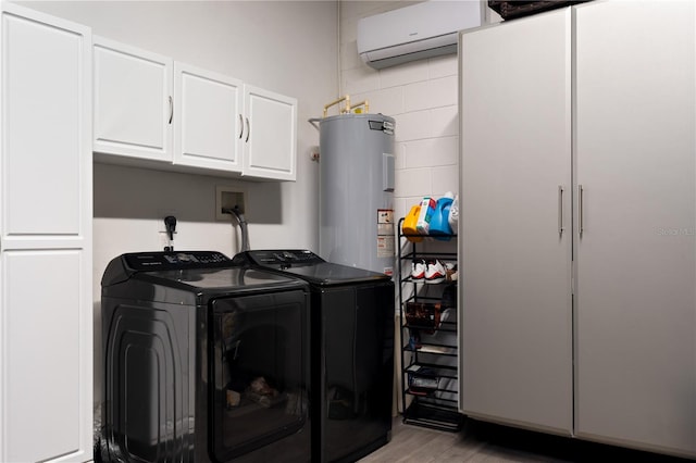 clothes washing area featuring cabinet space, a wall unit AC, washing machine and clothes dryer, light wood-style floors, and water heater