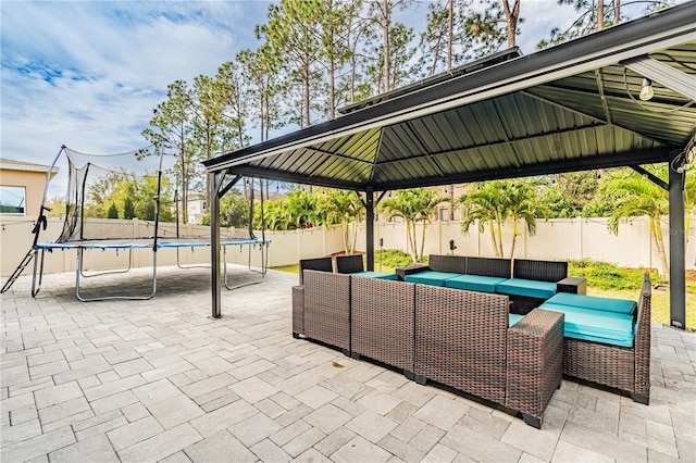 view of patio with a fenced backyard, a trampoline, an outdoor hangout area, and a gazebo