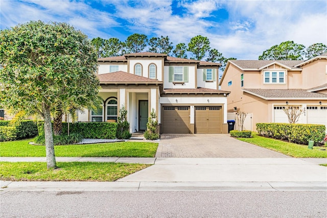 view of front of house featuring a garage, stucco siding, decorative driveway, and a front yard