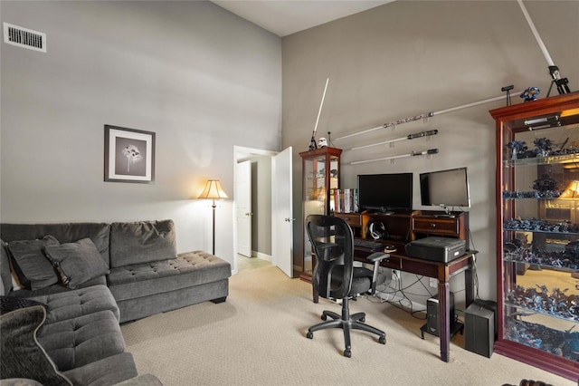 office with a towering ceiling, carpet flooring, and visible vents