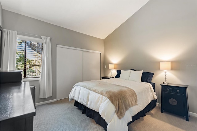 bedroom with light carpet, vaulted ceiling, a closet, and baseboards