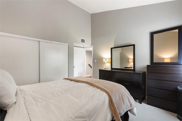 bedroom with a towering ceiling, a closet, visible vents, and carpet flooring