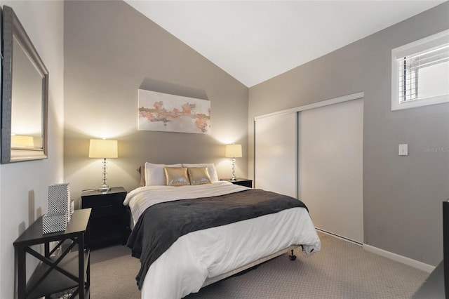 carpeted bedroom featuring lofted ceiling, a closet, and baseboards