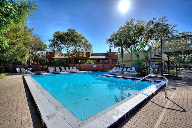 community pool with a patio area and fence