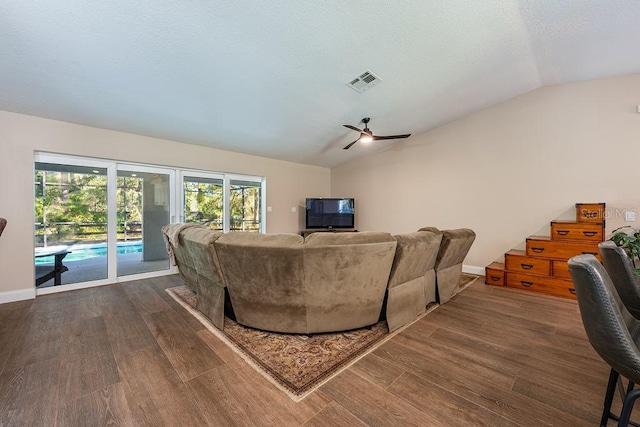 living area featuring visible vents, baseboards, vaulted ceiling, wood finished floors, and a textured ceiling