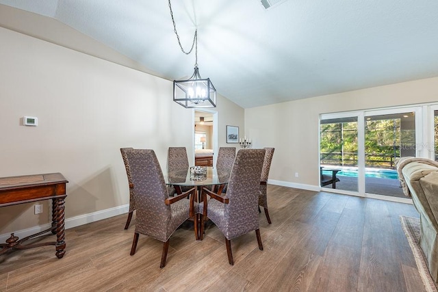 dining room featuring an inviting chandelier, baseboards, lofted ceiling, and wood finished floors