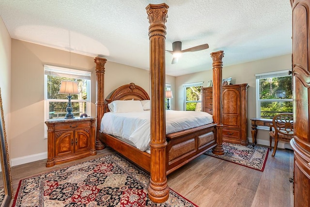 bedroom featuring multiple windows, a textured ceiling, and light wood-style flooring