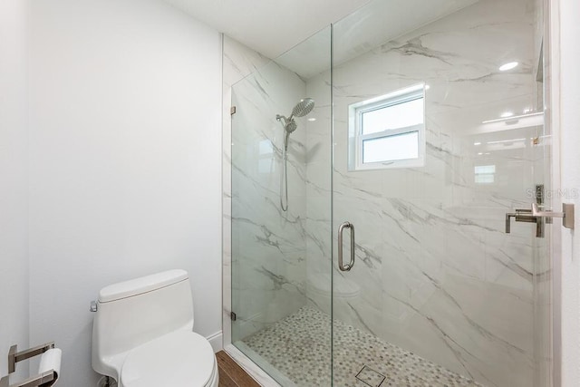 bathroom featuring a marble finish shower and toilet