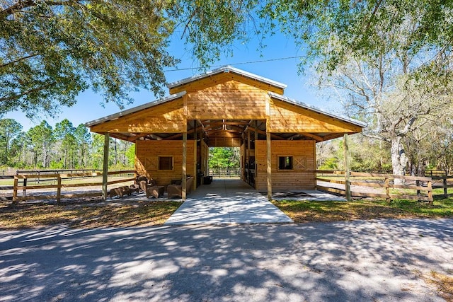 view of community featuring an attached carport, aphalt driveway, an outdoor structure, and an exterior structure