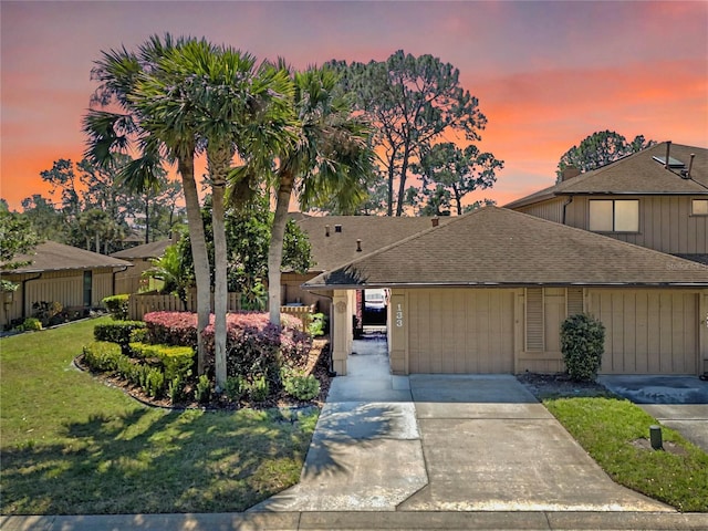 view of front facade with driveway, fence, a front yard, and a shingled roof