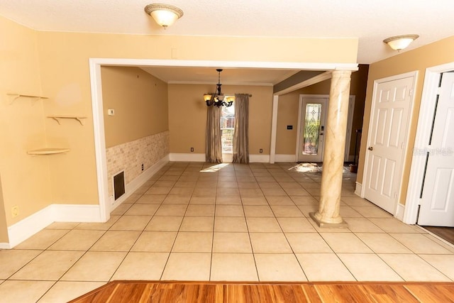 interior space featuring an inviting chandelier, light tile patterned flooring, baseboards, and ornate columns