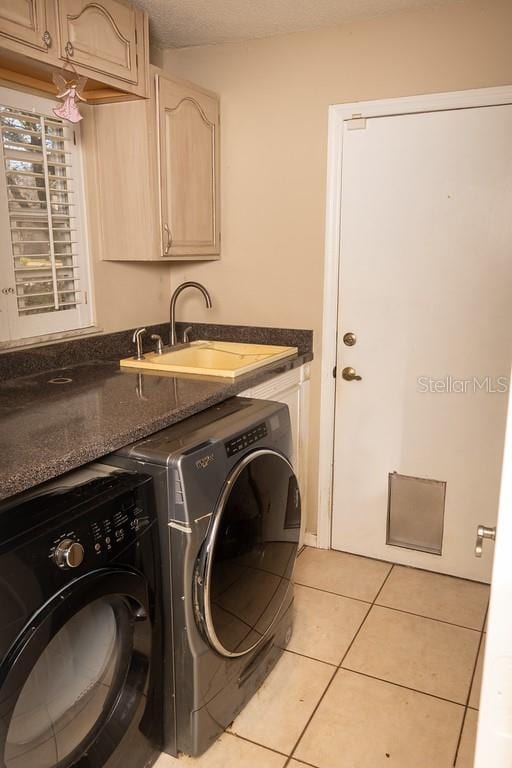 laundry room with light tile patterned flooring, cabinet space, a textured ceiling, independent washer and dryer, and a sink