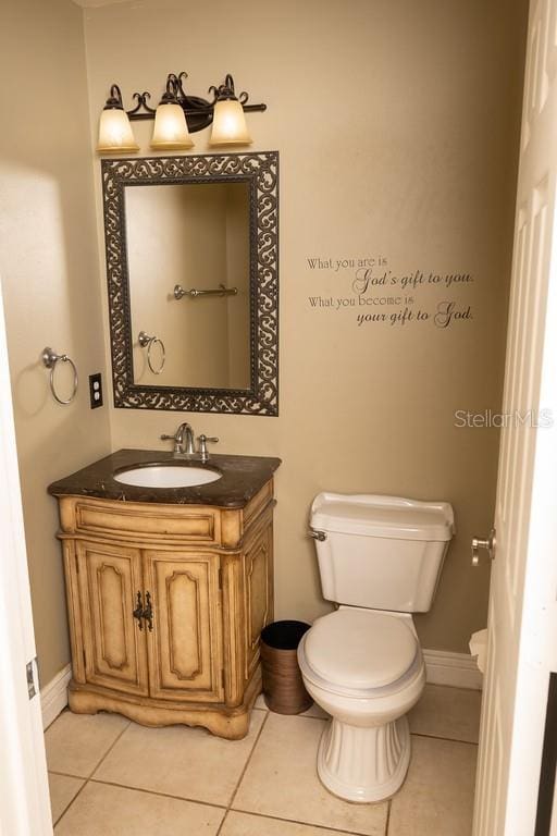 half bath with tile patterned flooring, toilet, and vanity