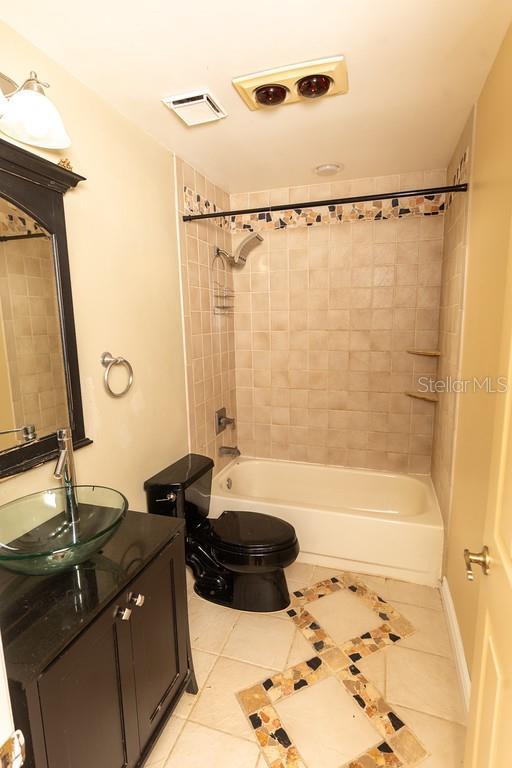 full bathroom featuring tile patterned floors, visible vents, toilet, and shower / washtub combination