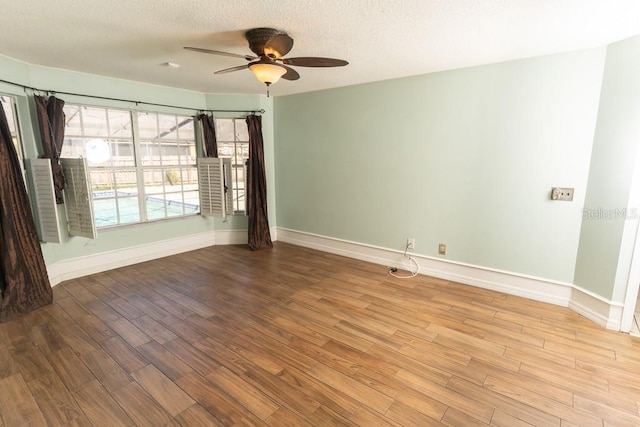 unfurnished room featuring a textured ceiling, baseboards, and wood finished floors