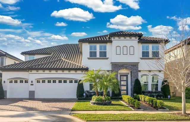 mediterranean / spanish-style house with a garage, decorative driveway, a tile roof, and stucco siding