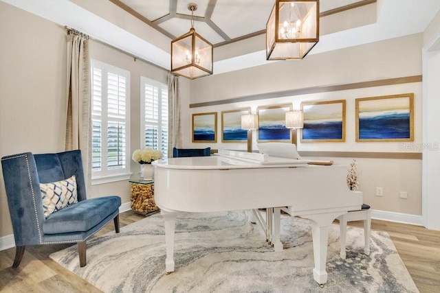 sitting room with wood finished floors, baseboards, and an inviting chandelier