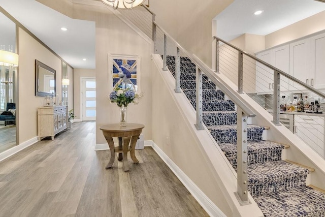 stairway featuring baseboards, wood finished floors, and recessed lighting