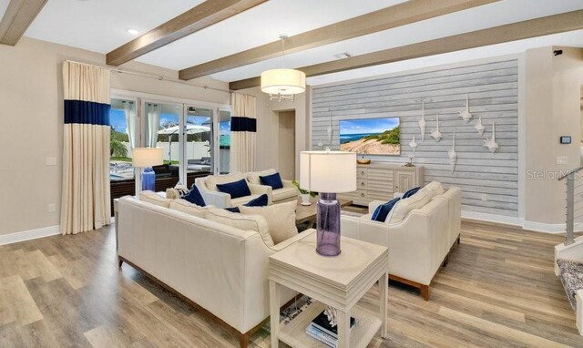 living area featuring wooden walls, beam ceiling, light wood-style flooring, and baseboards