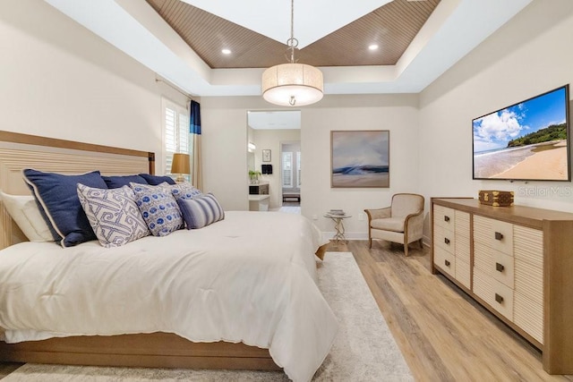 bedroom featuring baseboards, recessed lighting, a raised ceiling, and light wood-style floors