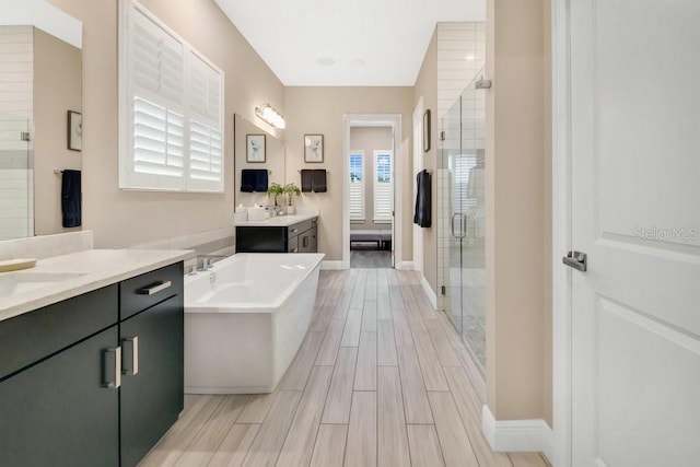 bathroom with wood finish floors, a stall shower, a freestanding tub, and baseboards