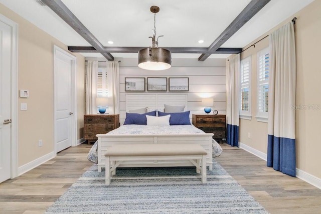 bedroom with light wood-type flooring, baseboards, and beam ceiling