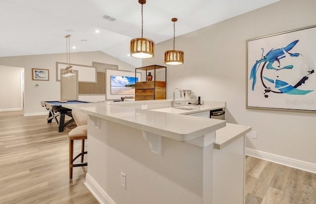 bar with decorative light fixtures, light wood finished floors, visible vents, vaulted ceiling, and baseboards