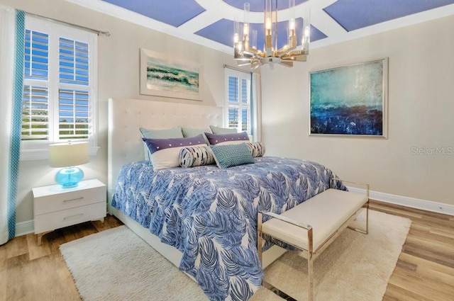 bedroom with baseboards, coffered ceiling, wood finished floors, and an inviting chandelier