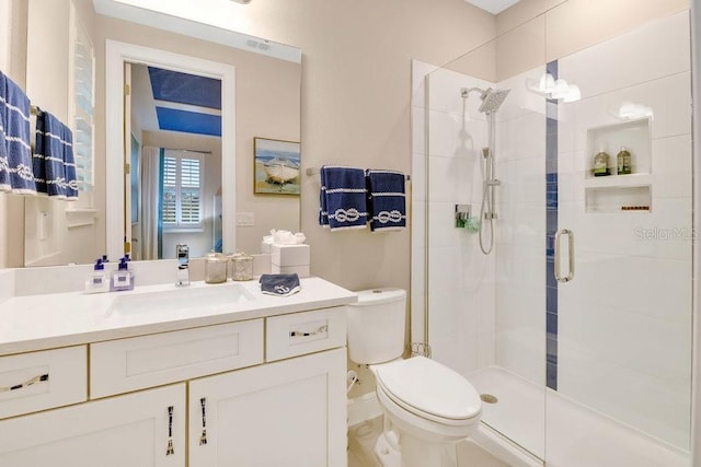 full bathroom featuring a stall shower, vanity, and toilet